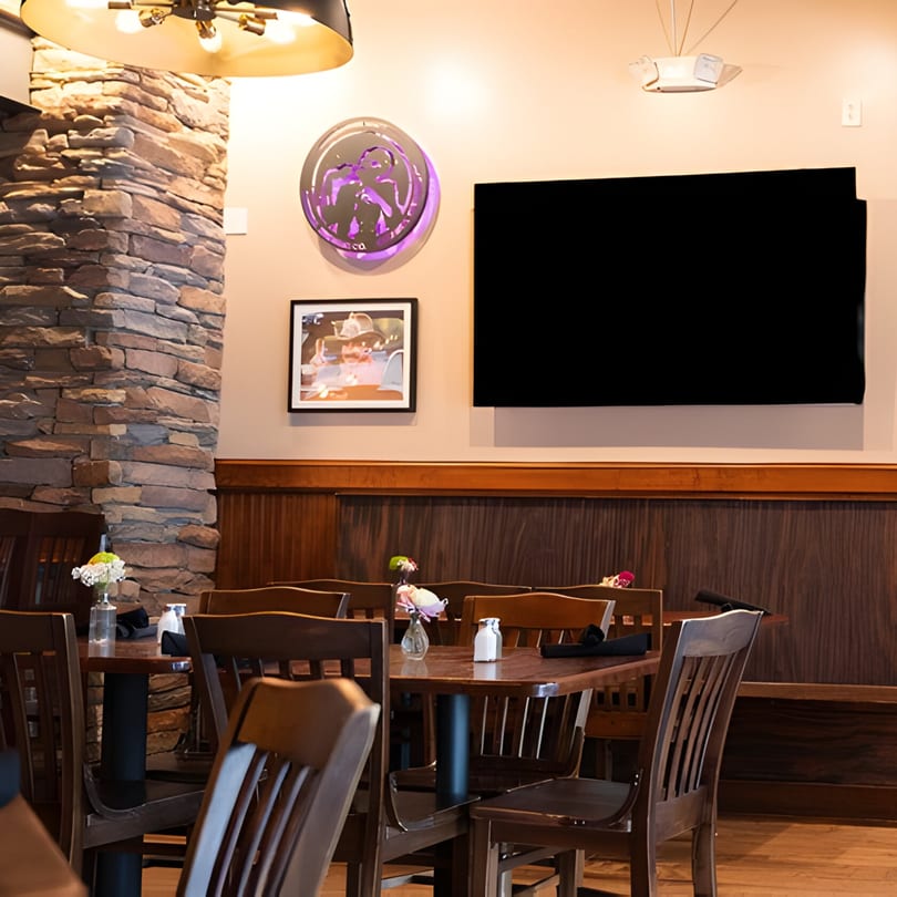 Interior of Mayworth's Public House with wooden tables and chairs, a stone pillar, and a large TV.
